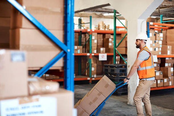 Shot of a young man moving boxes on a trolley in a warehouse