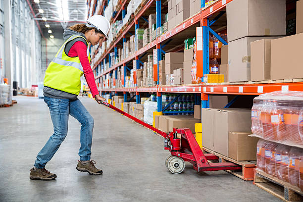 Worker pushing trolley with boxes in warehouse